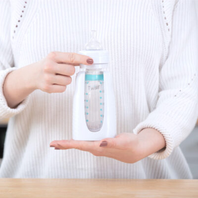 Hands holding a Squeeze bottle with a nipple connected via an adapter